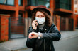 © Катя Іваськевич - young woman with mobile phone in the city in mask. coronavirus. covid-19.