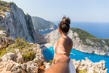 Woman Shakes Hands With Her Partner And From Behind They Watch The Shipwreck Beach In Zakynthos, Greece