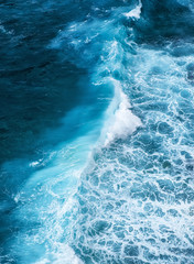 Wall Mural - waves and blue water as a background. view from high rock at the ocean surface. natural summer seasc