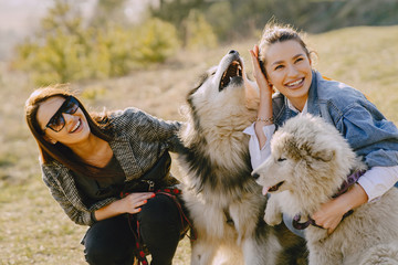 Wall Mural - Women in a spring forest. Girls with cute dogs. Stylish friends walks.