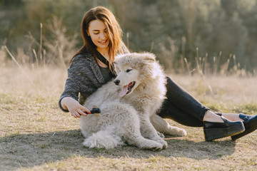 Wall Mural - Woman in a spring forest. Girl with cute dog. Brunette in a gray jacket.