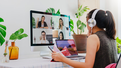 Asian business woman work from home with laptop, tablet and computer on table with meeting online and video conferencing.Concept of social distancing to stop the spread disease of Corona virus.