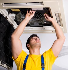 Repairman repairing ceiling air conditioning unit