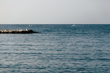 A walk through the streets of Bari, a city in the south of Italy. Two boats and a breakwater on the Mediterranean sea on the background of a clear sky.