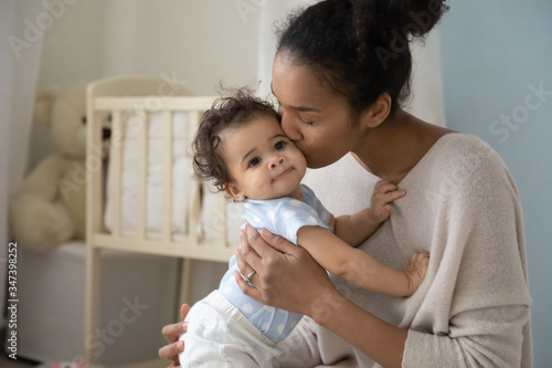 Loving young african American mother hold little newborn infant child kiss enjoy Tableau sur Toile