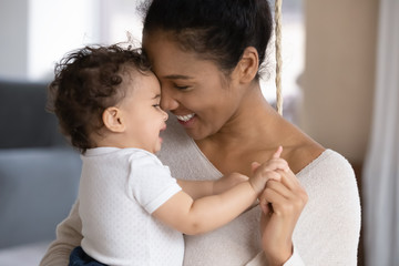 close up of happy young african american mother hug cuddle little infant or toddler, loving smiling 