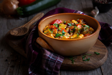 Chopped cooked vegetables on dark wood. Traditional ratatouille with zucchini, bell pepper and eggplant