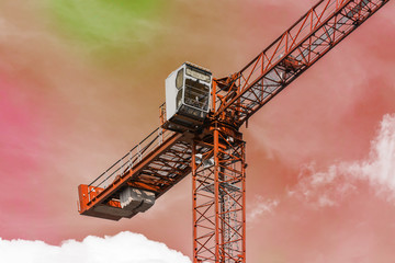 Red tower crane against pink sky with white clouds. Close up. Copy space.