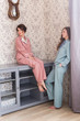 © satura_ - Two female sisters or friends relaxing at the living room. Girls in stylish pajamas. Full length portrait. Quarantine and stay at home concept.