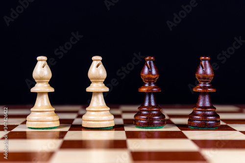 Fotomural four chess bishops on a chessboard on a black background