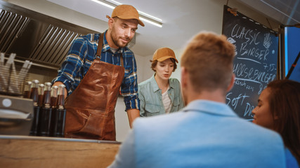 Happy Food Truck Employee Asks Young Couple about their Orders. Young People Order Tasty Street Fuud Burgers. Modern Hip Neighbourhood