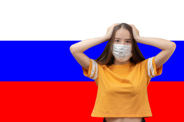 Wall Mural - Danger and panic due to coronavirus in Russia. Young girl in antibacterial medical mask holds her head, scared on the background of the flag with copyspace