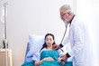 © eakgrungenerd - man doctor using stethoscope health check for women patients in hospital.