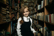 © rss_maxim - girl in a school uniform stands between shelves with books