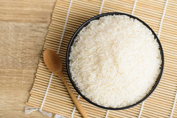 Organic Thai Jasmine rice grain in a bowl with spoon on wooden background, Top view