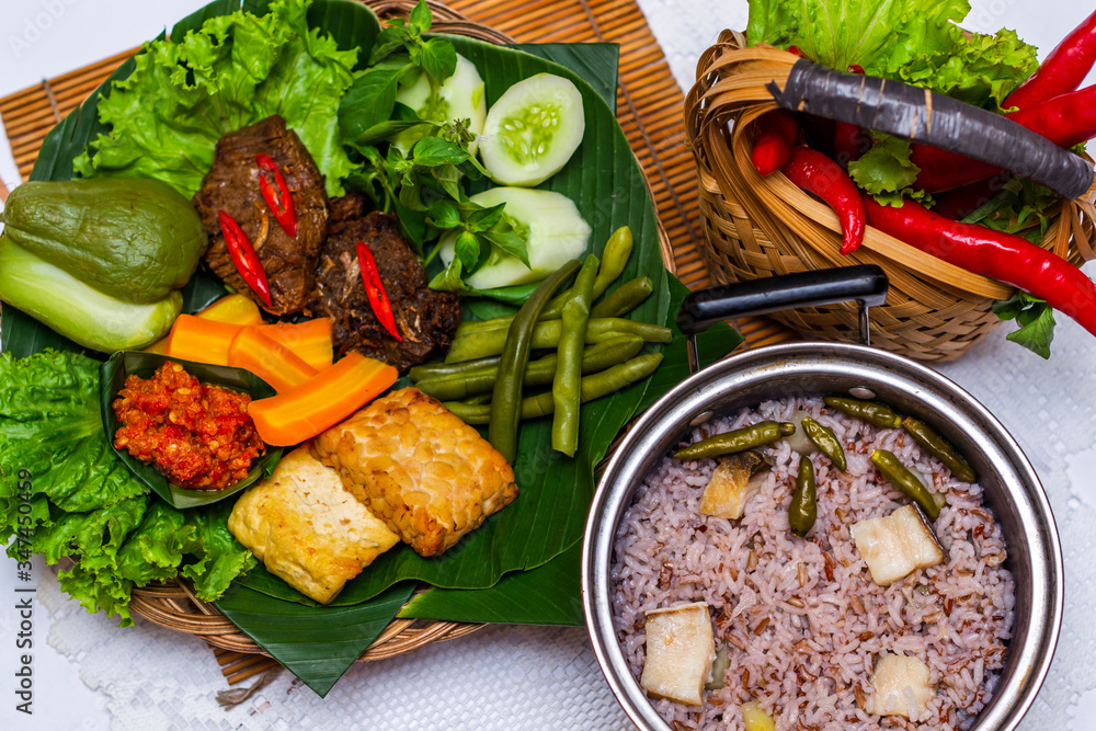 Indonesian traditional food nasi liwet with empal daging, tahu, sambal ...