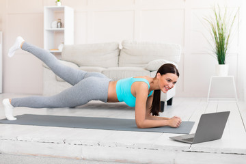 Sporty Girl Exercising At Laptop Standing In Plank At Home