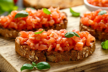 Wall Mural - Tomato bruschetta seasoned with basil on a rustic wooden board