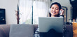 © weedezign - asian young woman listening music with headphone and streaming music from laptop on sofa relaxing at home