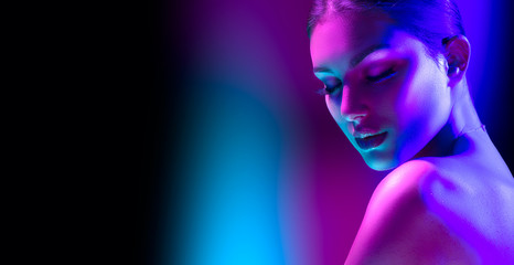 Wall Mural - High Fashion model woman in colorful bright neon lights posing in studio, night club. Portrait of beautiful girl in UV. Art design colorful make up. On colourful vivid background, art design.