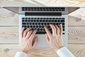 Poster - Top view of man's hands typing on laptop in sunny day. Coworking or working at home concept image.