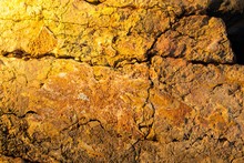 Closeup Of An Aged Yellow Rock With Cracks On It Under The Sunlight