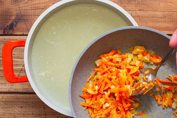 Step-by-step preparation of chicken soup with dumplings, step 3 - adding fried onions and carrots to the soup, top view, selective focus