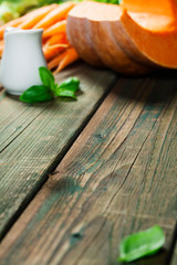 Wall Mural - Healthy food cooking. Fresh garden carrots, onions, pumpkins, ginger and spices on rustic wooden background