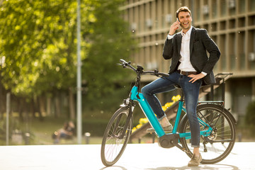 Young businessman on the ebike using mobile phone