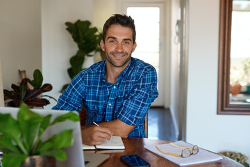 Smiling young man working from home in his living room