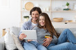 © Prostock-studio - Happy couple purchasing online, holding credit card and digital tablet
