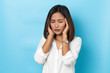 © suriya - asian young woman having headache on blue background