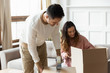 © fizkes - Happy young couple packing belonging in cardboard boxes in living room, moving day, family preparing to relocation into first new house, smiling husband sealing box with adhesive tape