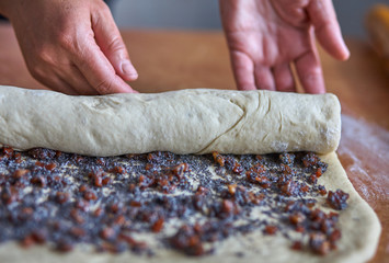 Wall Mural - Woman rolls dough with jam for baking.