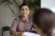 © fizkes - Close up happy young indian ethnic businesswoman talking about finance business project. Smiling diverse attractive female leader discussing sales presentation with workers in boardroom at meeting.