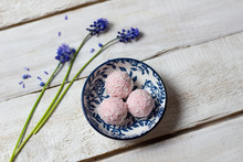 Pink Energy Balls With Red Currant Berries And Blue Grape Hyacinth Flowers On White Wooden Background