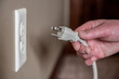 © Lost_in_the_Midwest - Caucasian hand gripping a three pronged power cord to insert into a power outlet