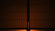 Silhouette behind sliding paper doors with lamp yellow backlight opening door and man entering room hall at night in wooden traditional Japanese house