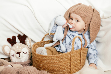 Wall Mural - A small boy is sitting in a wicker basket with a hat with rabbit ears