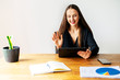 © Vadim Pastuh - Virtual meeting, video call. A young attractive woman is using tablet for online communicating on the distance. She sits at the table in the office with tablet in hand and waving hello into webcam