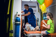 © Anna Kosolapova - Unconscious mother lying on a stretcher in an ambulance car, a paramedic providing her first aid