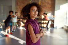 Active Kid. Portrait Of A Girl Smiling At Camera Before Warming Up, Exercising Together With Other Kids And Trainer In Gym. Sport, Healthy Lifestyle, Active Childhood Concept
