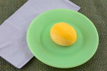 Wall Mural - Mango ice cream mochi ball on green dessert plate with lavender napkin