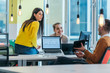 © qunica.com - Group of professional coworkers ( team ) working on a desk in a modern office on their laptops while talking to each other. Business photo.