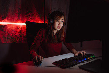 Pro player gamer young asian woman playing online video game shooting fps tournament ranking cyber internet at night red neon light room with gaming headset and keyboard on championship event.