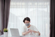 © Kiattisak - Asian man wearing mask pump hand gel alcohol cleaning sanitizer working from home with laptop computer prevent the spread of coronavirus quarantine workplace with protective stay home.