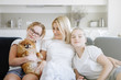 © olgasparrow - Woman with two daughters and dog sits on sofa.