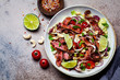 © vaaseenaa - Thai beef salad with vegetables and nuts in a white bowl on dark background, top view. Asian food concept.
