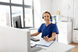 medicine, technology and healthcare concept - happy smiling female doctor or nurse with headset and computer working at hospital
