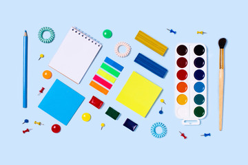 Wall Mural - Photo to illustrate education. School supplies on blue background. Back to school flat lay picture.